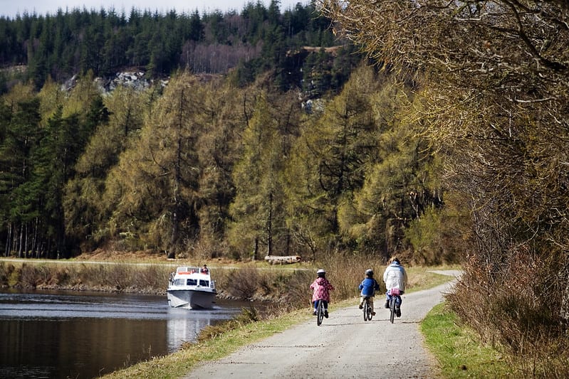 Adult and children riding a bike by a lake and forrest